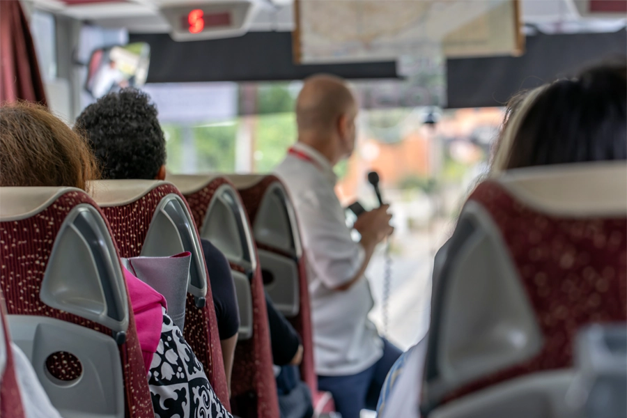 Guia de turismo dá orientações sobre o pásseio aos passageiros num ônibus