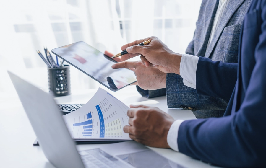 Imagem: close de dois técnicos em contabilidade conversando enquanto analisam relatórios.