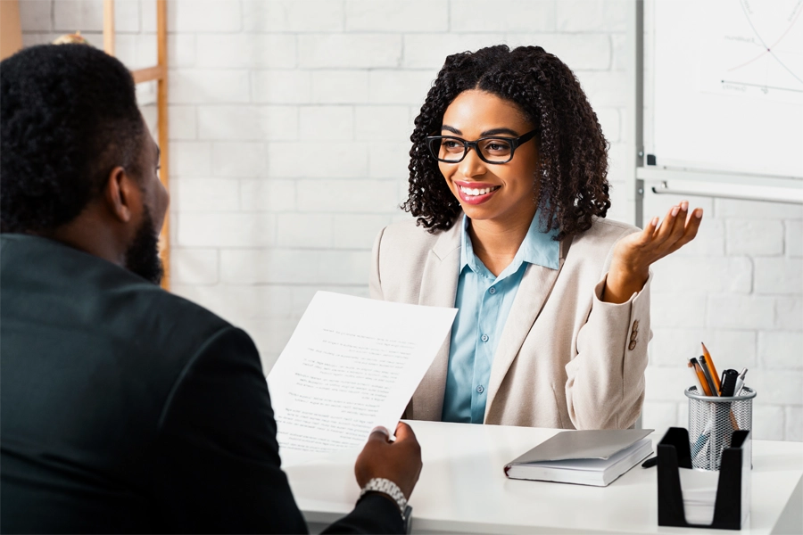 Imagem: um funcionário do departamento pessoal conversa com uma funcionária sobre benefícios da empresa.