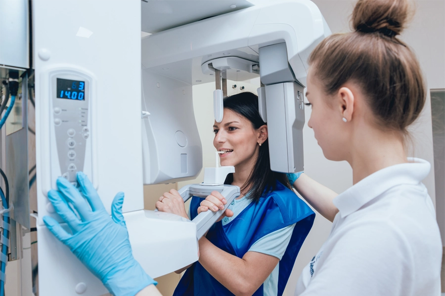 Imagem: paciente odontológica fazendo exame de raio-x dos dentes sob supervisão e auxílio de uma radiologista.