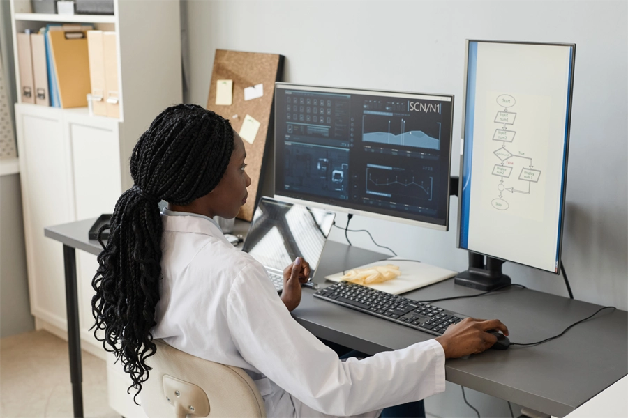 Imagem: uma mulher negra, gestora de TI, está sentada de frente para um computador trabalhando na análise de dados em gráfico.