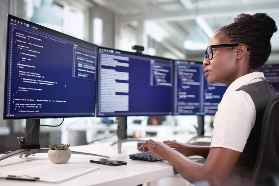 Técnica em informática trabalhando com múltiplas telas