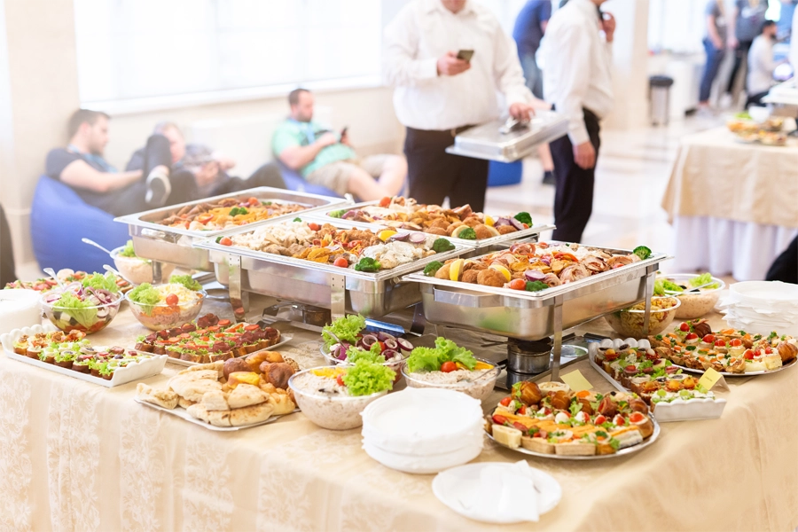 Imagem: mesa com travessas de buffet de comidas quentes e pratos para servir.