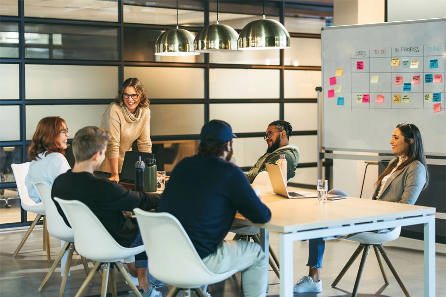Imagem: membros de uma equipe de publicidade se reunem em volta de uma mesa para discutir demandas de trabalho da agência onde estão.
