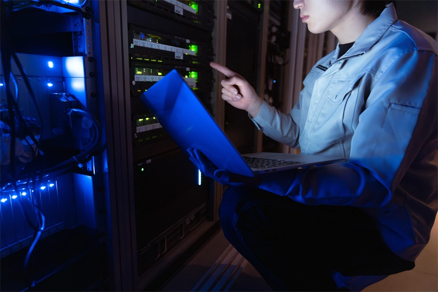 Imagem: técnico em redes de computadores analisando um problema com ajuda de um notebook.