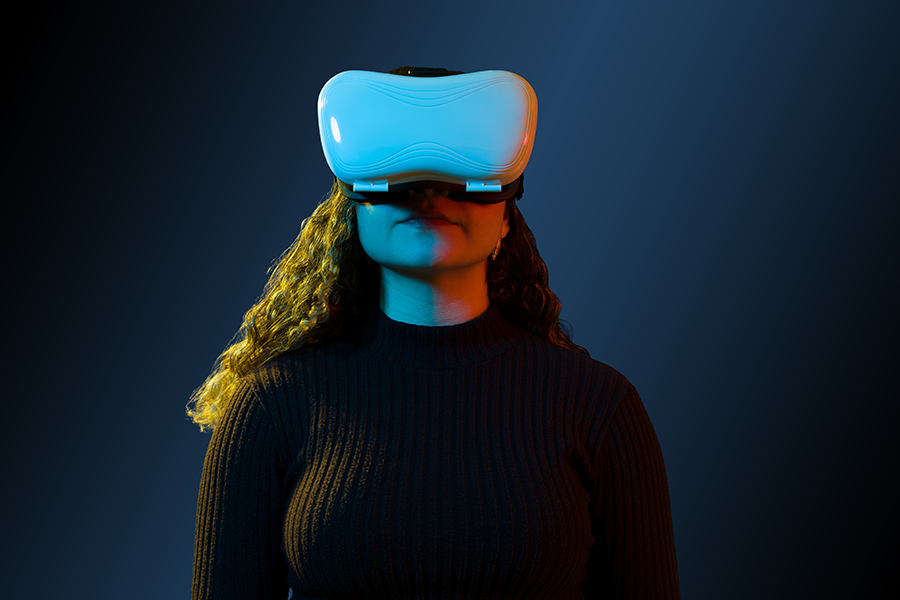 Uma mulher de cabelos cacheados e soltos na altura dos ombros utilizando óculos de realidade virtual para ingressar no metaverso.