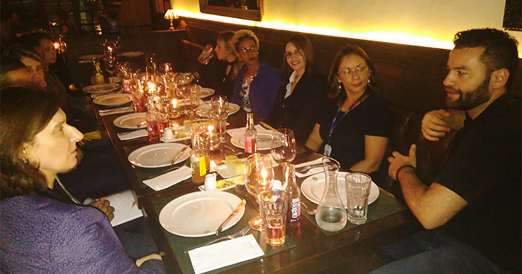 Alunos conversam sentados ao redor de mesa de restaurante Alunos conversam sentados ao redor de mesa de restaurante