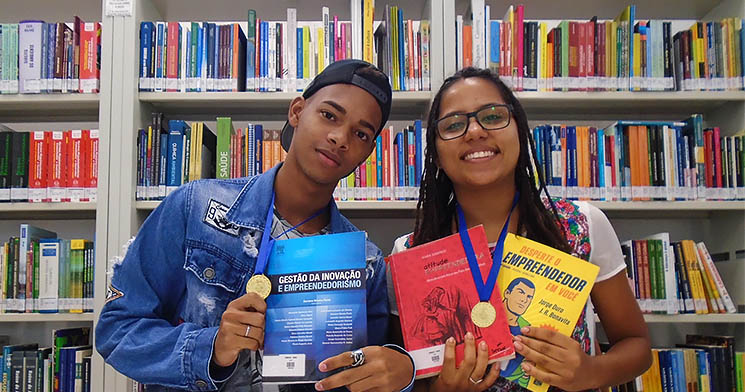Aluno e aluna posam lado a lado segurando livros Aluno e aluna posam lado a lado segurando livros