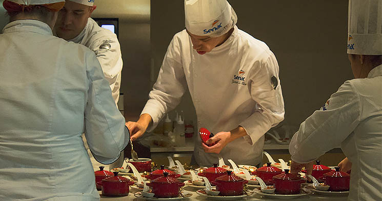 Dois alunos com dólmãs finalizam pratos durante evento Vinhos de Portugal Dois alunos com dólmãs finalizam pratos durante evento Vinhos de Portugal