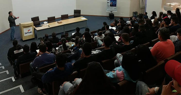 Plateia acompanha palestrando falando no palco do auditório Plateia acompanha palestrando falando no palco do auditório