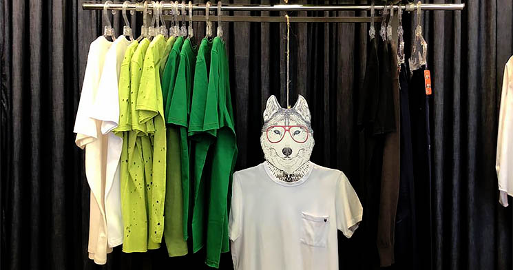 Manequim com rosto de lobo veste camiseta branca pendurado em arara de camisetas coloridas Manequim com rosto de lobo veste camiseta branca pendurado em arara de camisetas coloridas