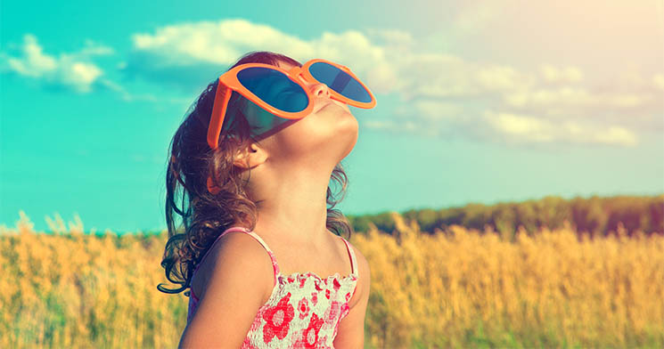 Imagem de menina com grandes óculos de sol com céu azul e mata ao fundo Imagem de menina com grandes óculos de sol com céu azul e mata ao fundo