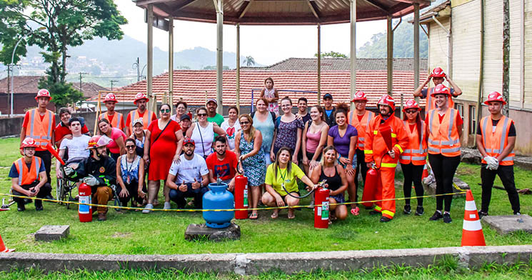 Pessoas reunidas em área externa com grama, com extintores e botijão de gás Pessoas reunidas em área externa com grama, com extintores e botijão de gás