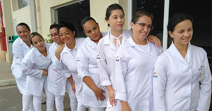 Oito alunas do curso Técnico em Enfermagem utilizando jalecos brancos com logo do Senac posam para foto em frente à entrada do Hospital Oito alunas do curso Técnico em Enfermagem utilizando jalecos brancos com logo do Senac posam para foto em frente à entrada do Hospital