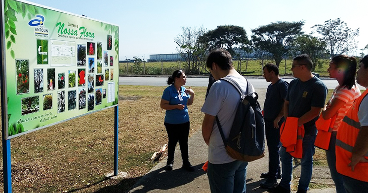 grupo de pessoas ao ar livre, em uma empresa, observando a explicação de uma funcionária. grupo de pessoas ao ar livre, em uma empresa, observando a explicação de uma funcionária.