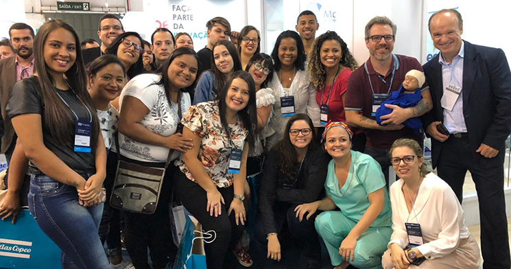 Público participante da atividade do Senac posa para foto. Um deles segura o boneco bebê que integra a simulação do parto. Público participante da atividade do Senac posa para foto. Um deles segura o boneco bebê que integra a simulação do parto.